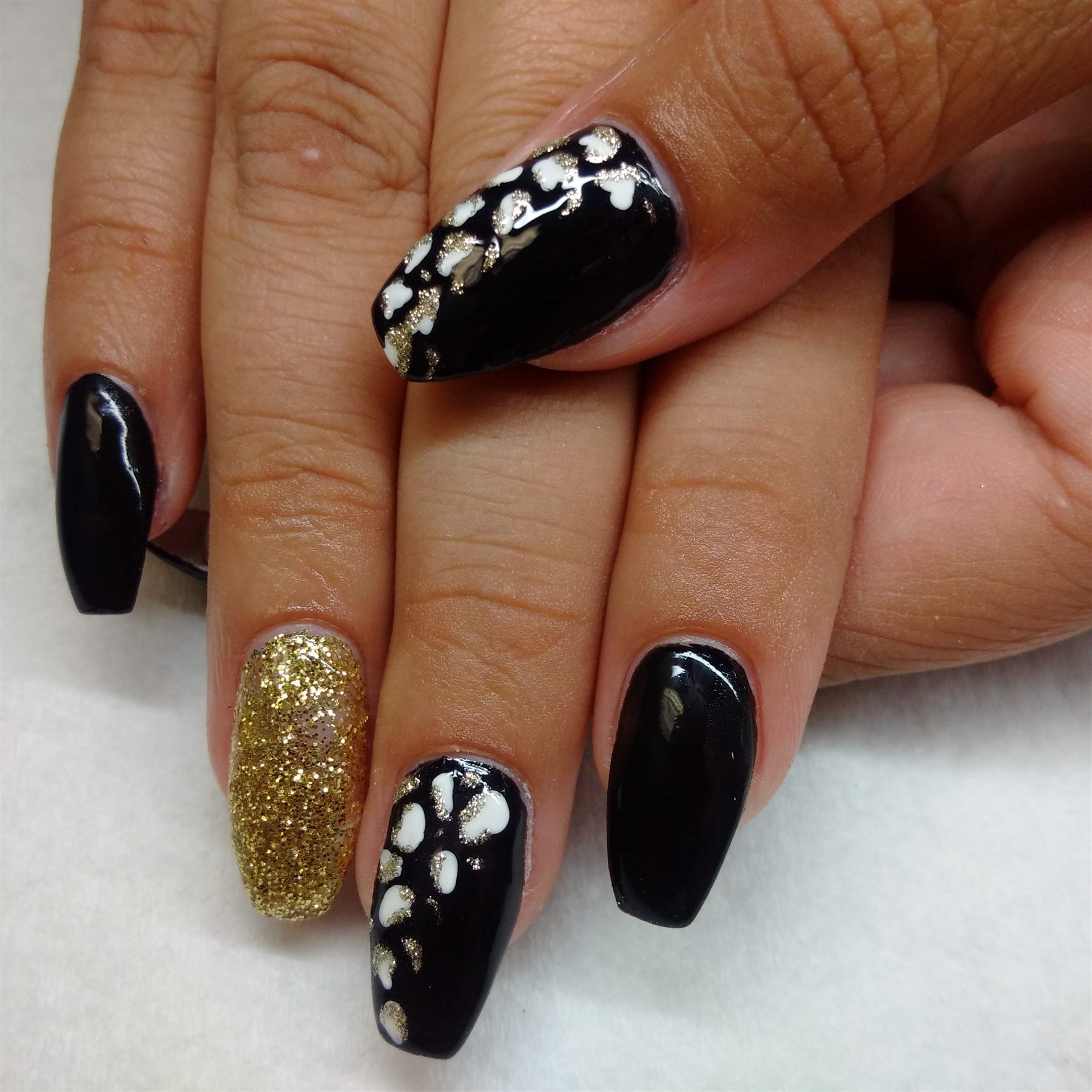 Black nails with gold glitter and leopard-print accent art