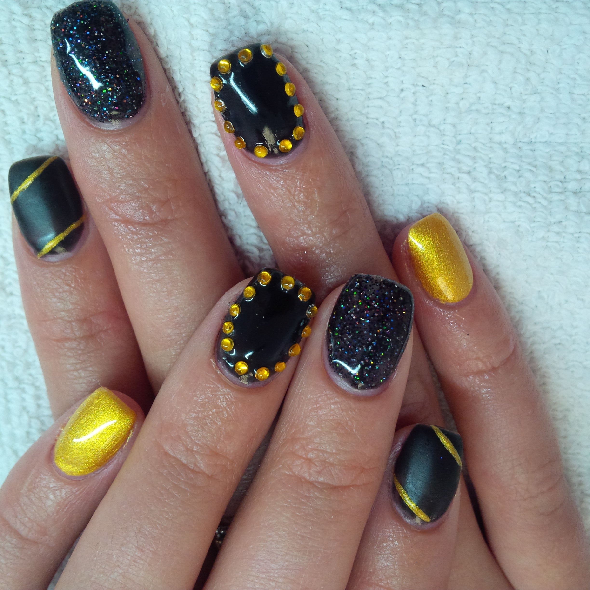 Black and gold nails with glitter and studded accents