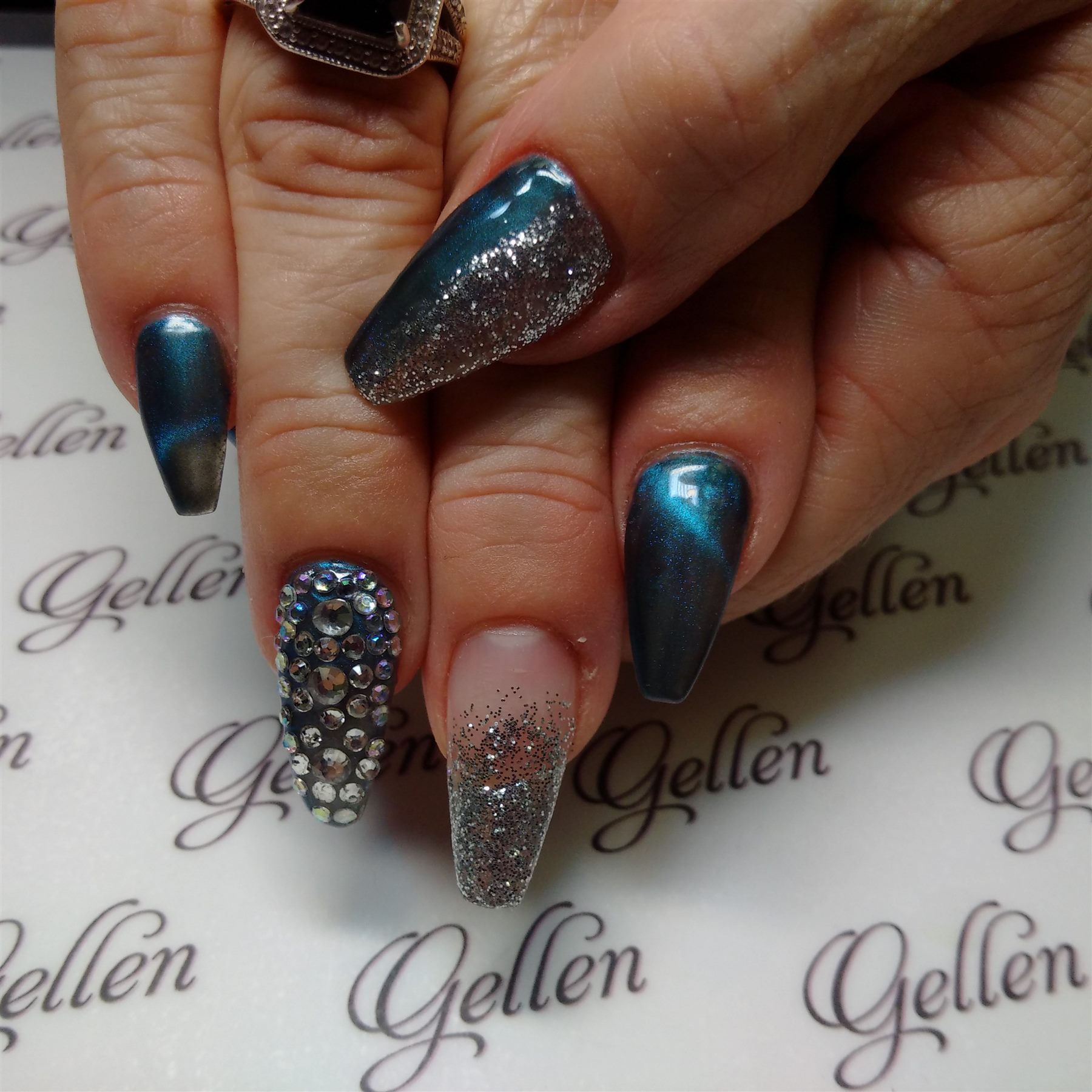 Deep teal nails with silver glitter and crystal embellishments