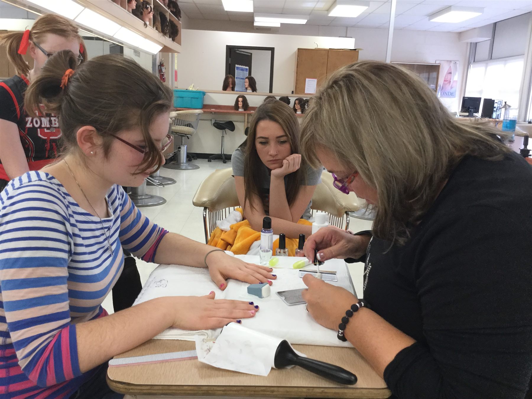 Nail educator demonstrating manicure techniques to high school students