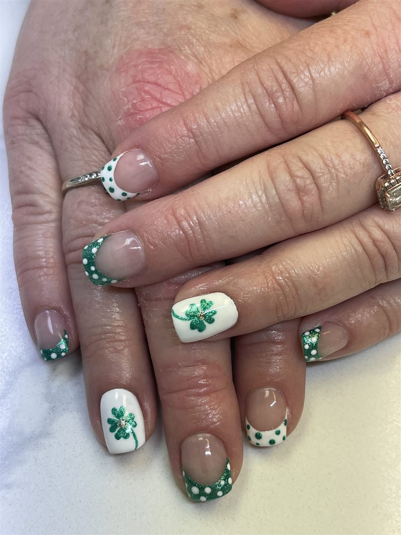 Green and white French nails with shamrock nail art