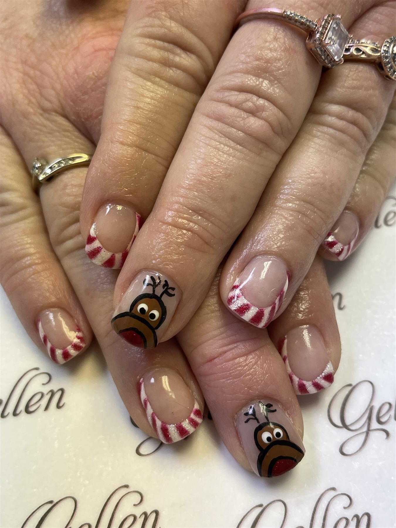 Candy-cane French nails with hand-painted reindeer accents