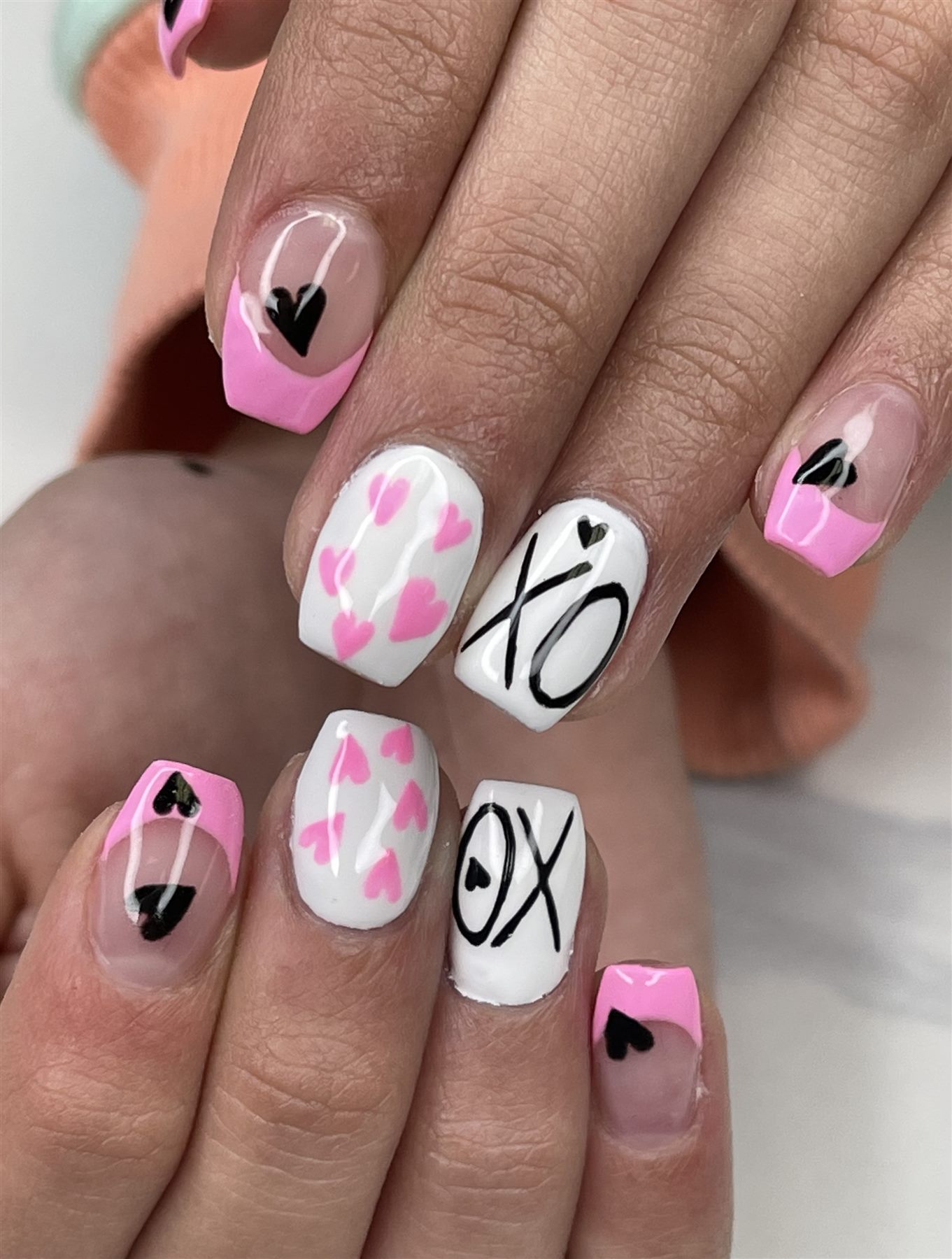 Pink black and white Valentine nails with hearts and XO lettering
