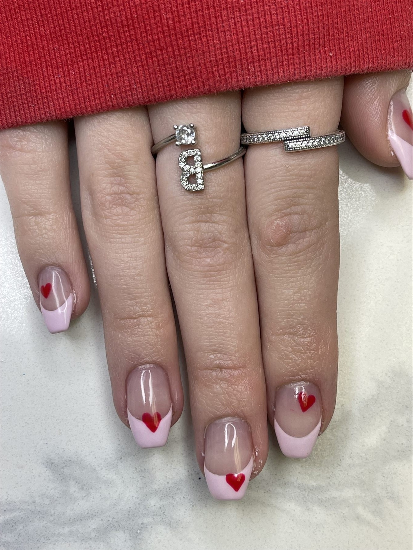 Pale pink French manicure with small red heart accents