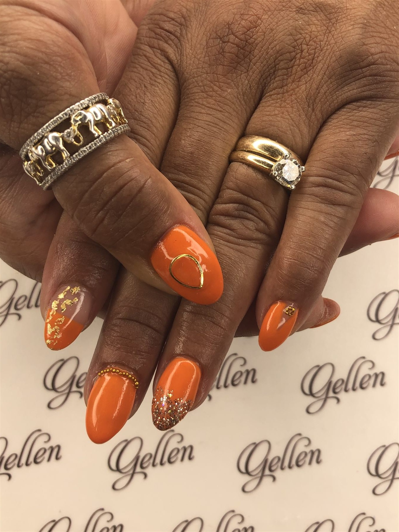Orange nails with gold foil glitter and metal accents