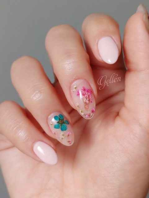 Close-up view of blush pink pressed flower nail art