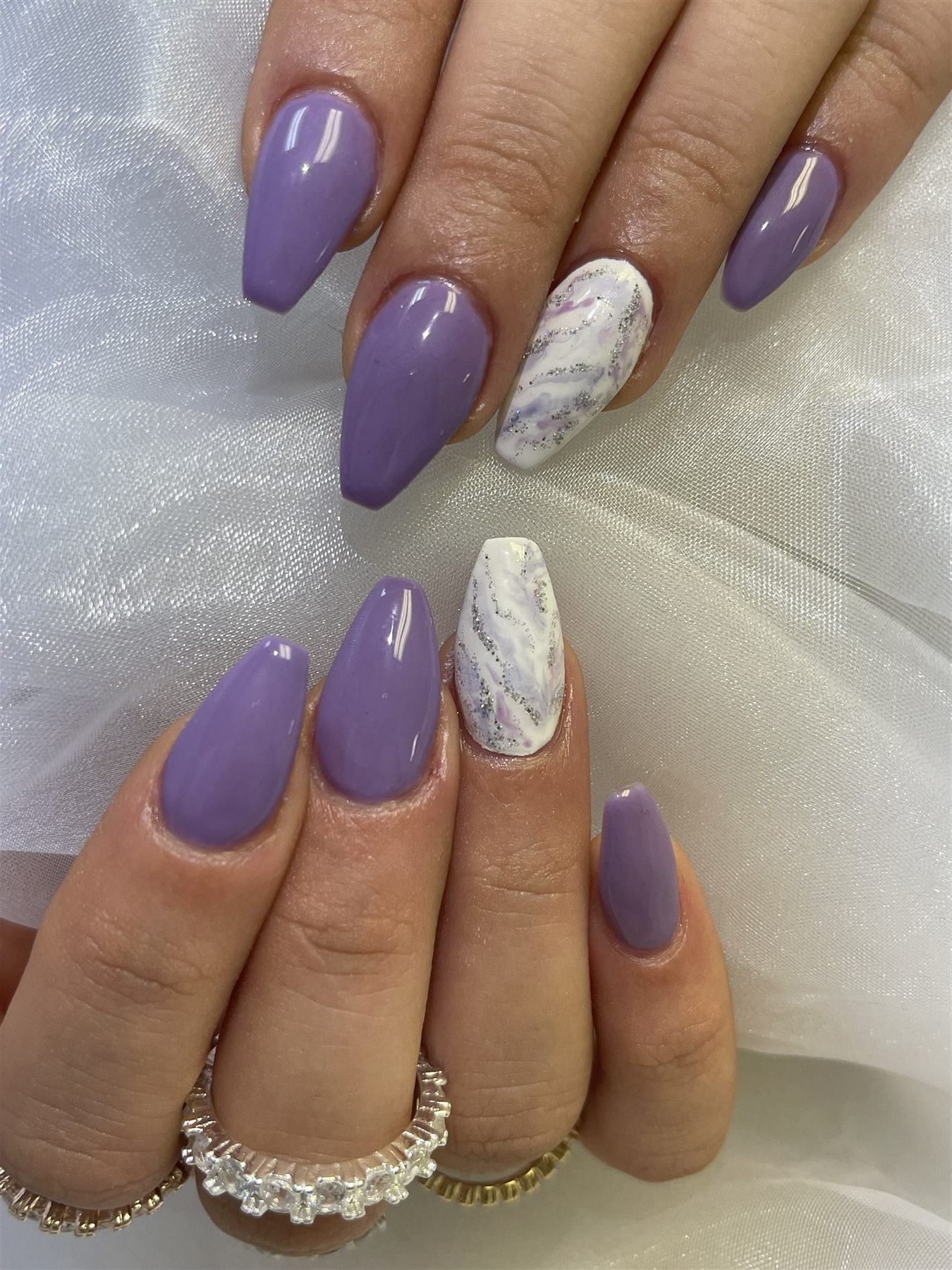 Lavender nails with white marble and silver glitter accents