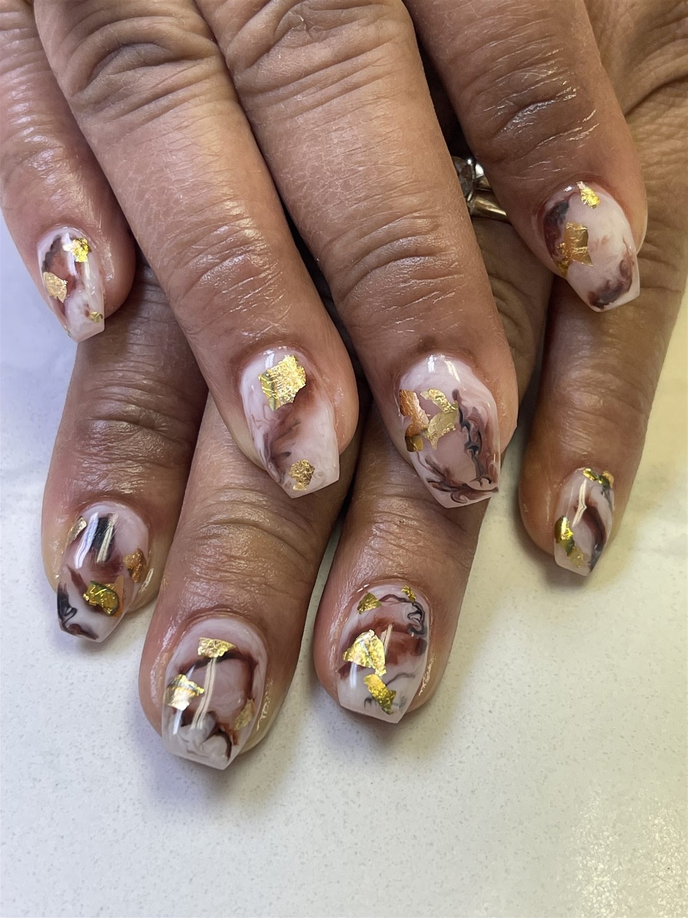 Blush marble nails decorated with scattered gold foil